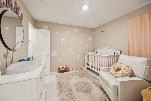 bedroom with light tile patterned floors, baseboards, a sink, a crib, and wallpapered walls
