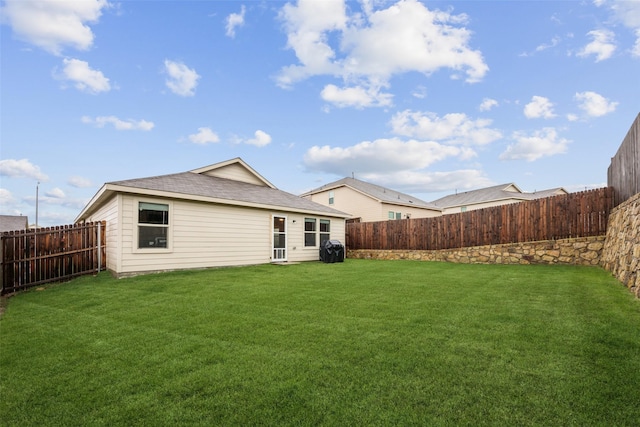 back of house with a lawn and a fenced backyard