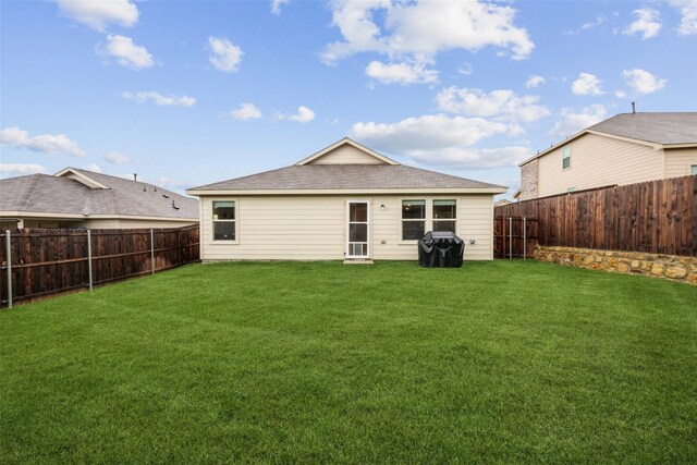 rear view of property with a lawn, a fenced backyard, and roof with shingles