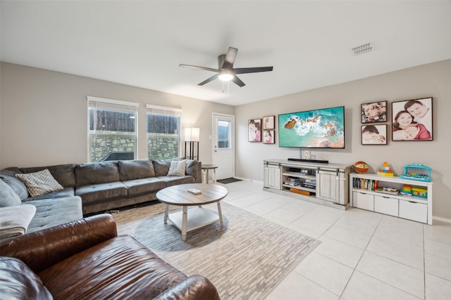 living area with visible vents, baseboards, ceiling fan, and light tile patterned flooring
