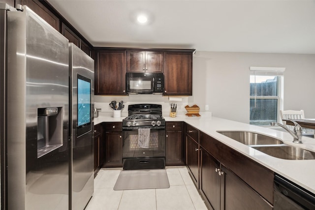 kitchen with a sink, light countertops, black appliances, and light tile patterned flooring