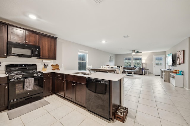 kitchen with dark brown cabinets, a sink, light countertops, light tile patterned floors, and black appliances