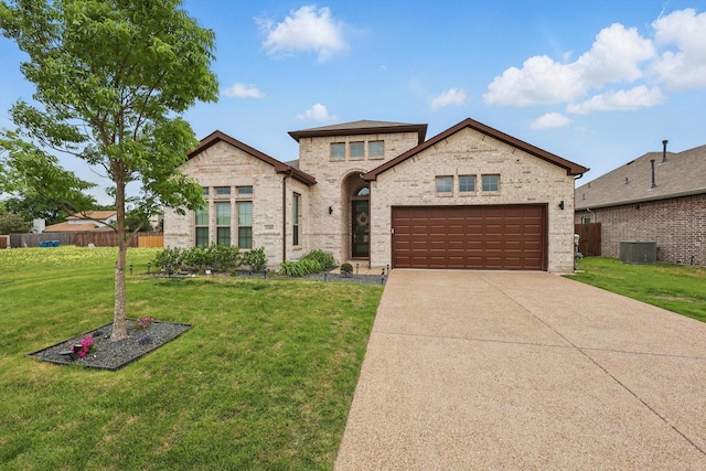 french country inspired facade with fence, an attached garage, a front yard, central AC unit, and concrete driveway