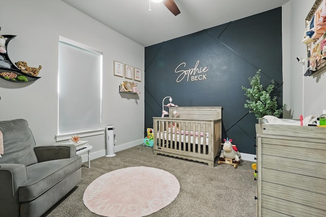bedroom with carpet floors, a nursery area, baseboards, and a ceiling fan