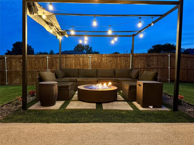 patio at twilight with a fenced backyard and an outdoor living space with a fire pit