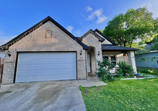 view of front facade featuring a front lawn, stone siding, a garage, brick siding, and driveway