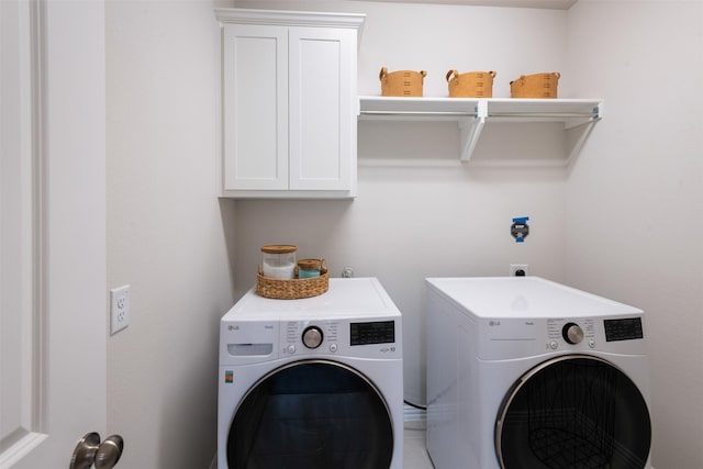 clothes washing area with separate washer and dryer and cabinet space