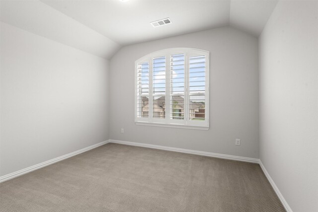 carpeted spare room featuring baseboards, vaulted ceiling, and visible vents