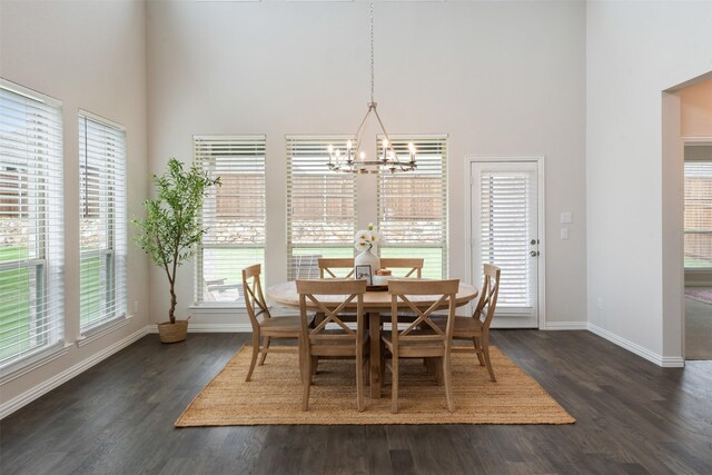 dining room with an inviting chandelier, dark wood-type flooring, baseboards, and a towering ceiling