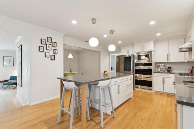 kitchen with ornamental molding, dark countertops, a center island, recessed lighting, and stainless steel appliances