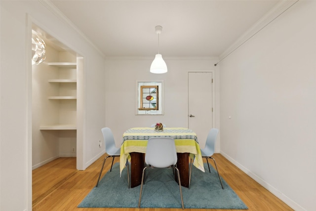 dining space with built in features, baseboards, ornamental molding, and light wood-style flooring