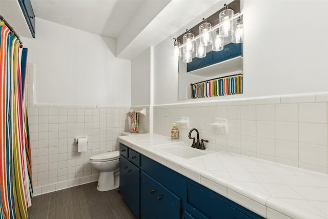 full bathroom featuring wainscoting, vanity, toilet, tile walls, and curtained shower