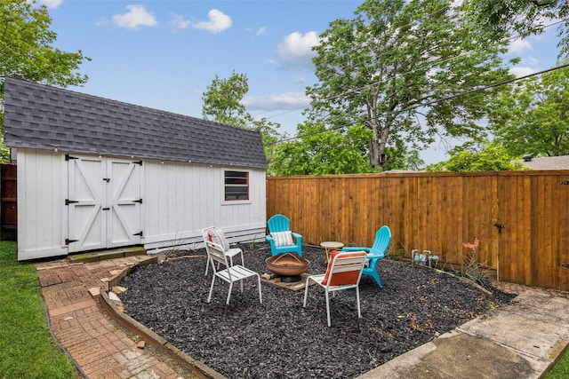 view of yard featuring an outdoor structure, a fenced backyard, a fire pit, and a shed
