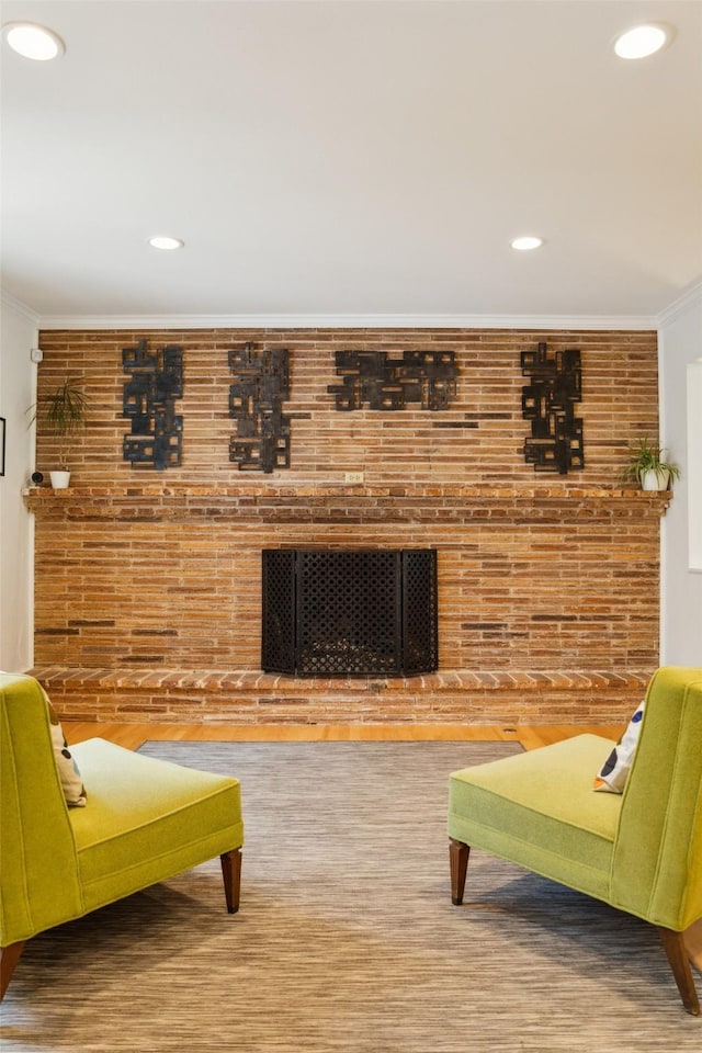living area featuring ornamental molding, a brick fireplace, recessed lighting, and brick wall