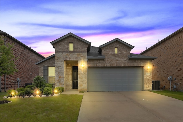 view of front of home with central air condition unit, an attached garage, driveway, and stone siding