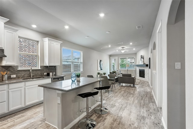 kitchen with dark countertops, a sink, a center island, white cabinetry, and open floor plan