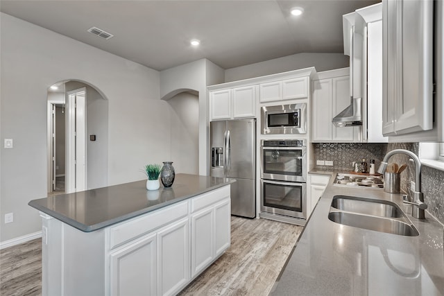 kitchen featuring visible vents, arched walkways, light wood-type flooring, a sink, and stainless steel appliances