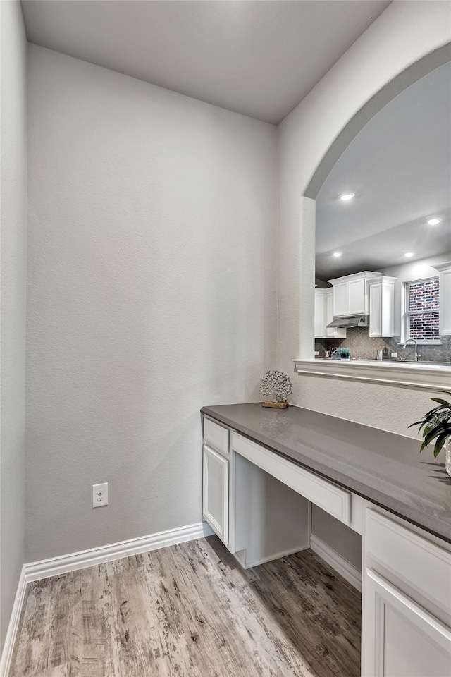 office area featuring arched walkways, wood finished floors, a sink, baseboards, and recessed lighting