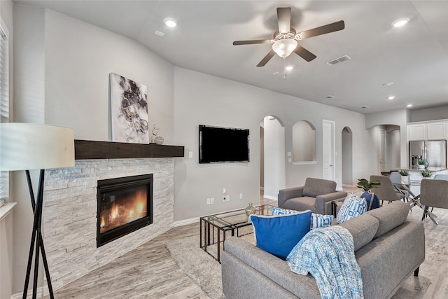living room featuring a fireplace, a ceiling fan, wood finished floors, and visible vents