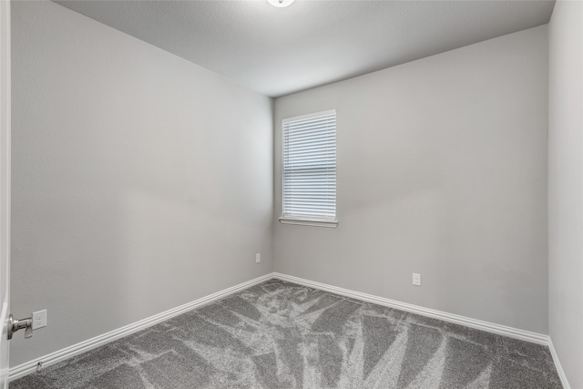carpeted empty room featuring baseboards