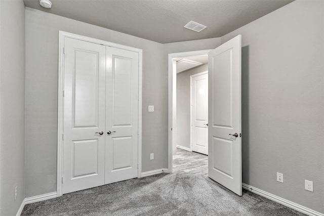 unfurnished bedroom featuring visible vents, carpet, baseboards, and a closet