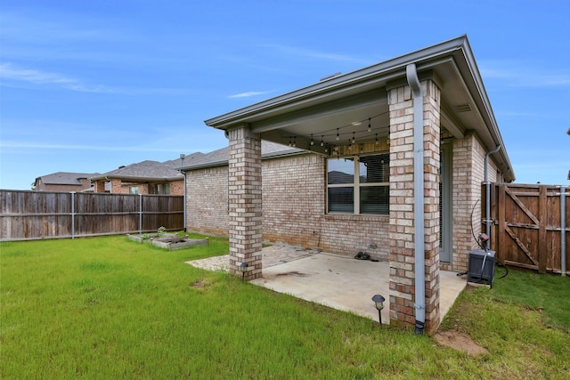 back of house featuring brick siding, a fenced backyard, central AC unit, a patio, and a yard