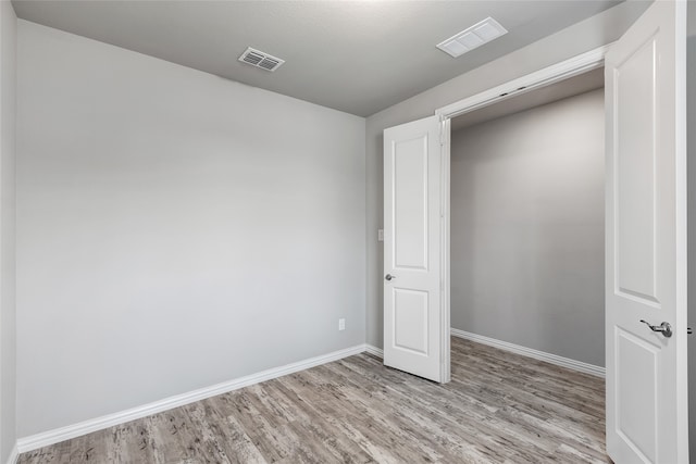 unfurnished bedroom with baseboards, light wood finished floors, and visible vents