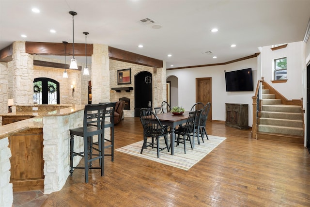 dining space featuring arched walkways, recessed lighting, wood finished floors, bar area, and stairway