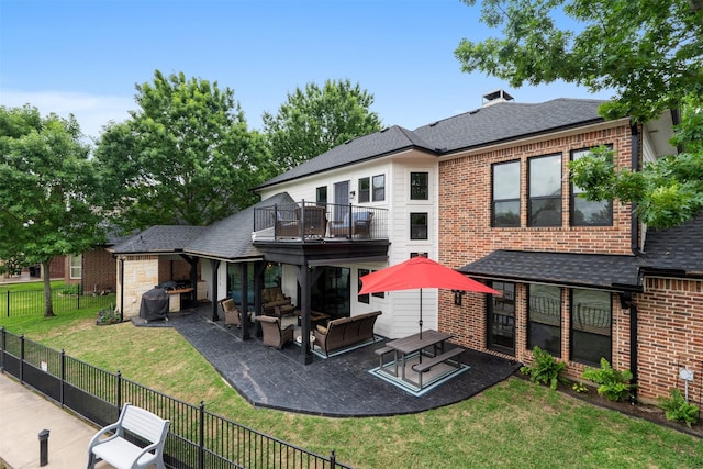 back of property featuring a balcony, a fenced backyard, brick siding, a patio area, and a lawn