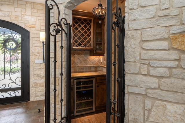 wine area with a dry bar, wine cooler, and a chandelier
