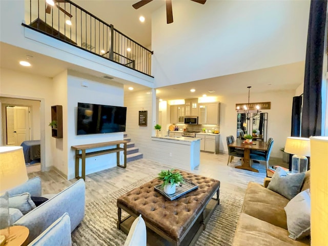 living room featuring recessed lighting, a towering ceiling, and ceiling fan with notable chandelier