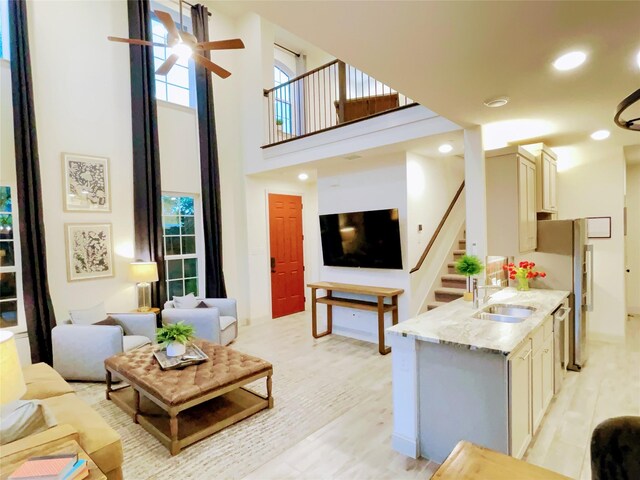 living area with light wood-style flooring, stairs, a towering ceiling, ceiling fan, and recessed lighting