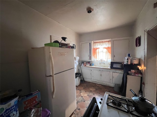 kitchen featuring freestanding refrigerator, white cabinets, and black microwave