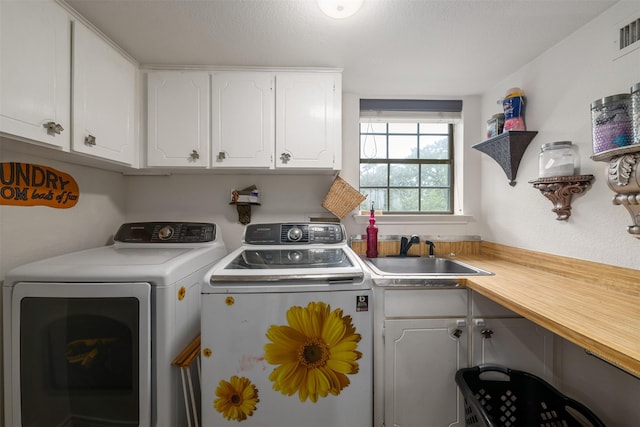 laundry area featuring cabinet space, visible vents, washer and clothes dryer, and a sink
