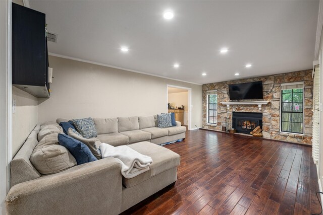 living room with crown molding, recessed lighting, a stone fireplace, and dark wood-style floors