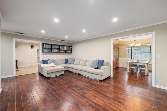 living area featuring crown molding, an inviting chandelier, wood-type flooring, baseboards, and visible vents