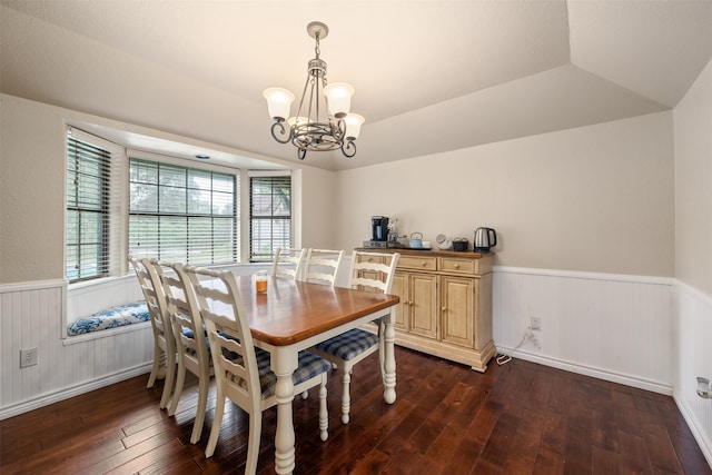 dining area featuring dark wood-style flooring, a chandelier, lofted ceiling, and a wainscoted wall