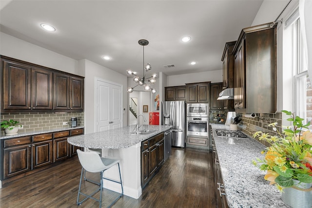 3608 Delta Dr, Mckinney, TX 75071 - kitchen featuring stainless steel appliances, a sink, tasteful backsplash, dark brown cabinets, and light stone counters