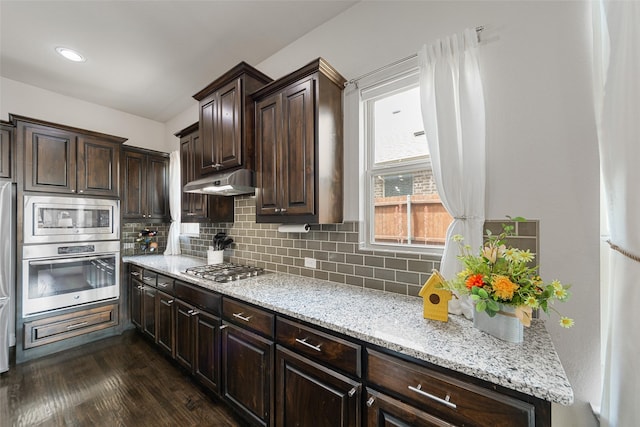 3608 Delta Dr, Mckinney, TX 75071 - kitchen with appliances with stainless steel finishes, backsplash, dark brown cabinetry, and under cabinet range hood