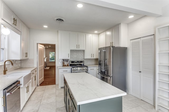 kitchen with stainless steel appliances, a kitchen island, white cabinetry, backsplash, and recessed lighting
