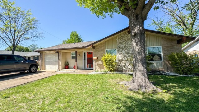 view of front of property with an attached garage, driveway, stone siding, and a front yard