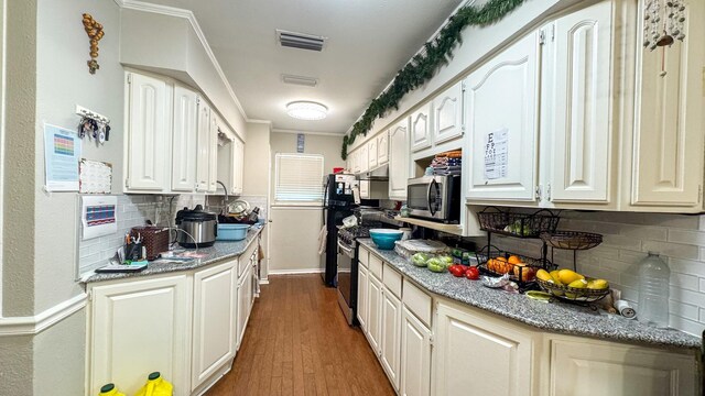 kitchen featuring stainless steel appliances, white cabinetry, dark wood-type flooring, backsplash, and visible vents