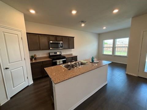 1109 Colonial Bluff Ln, Princeton, TX 75407 - kitchen with visible vents, dark wood-style flooring, dark brown cabinets, a sink, and appliances with stainless steel finishes