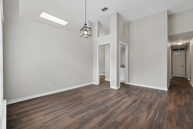 unfurnished dining area featuring baseboards, visible vents, dark wood-style floors, and high vaulted ceiling