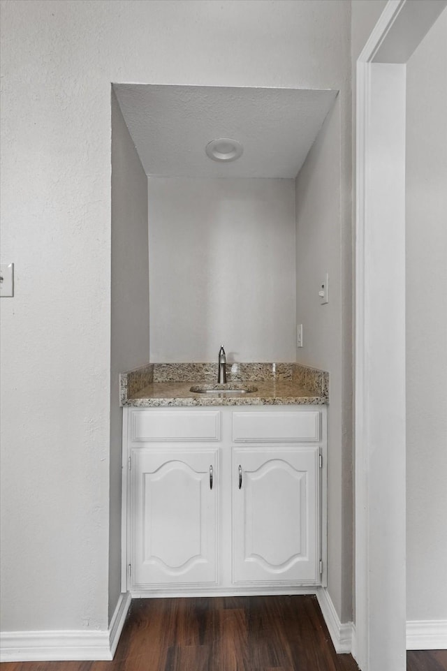 bathroom featuring baseboards, wood finished floors, and vanity