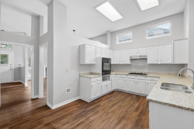 kitchen with light stone countertops, a sink, black oven, a towering ceiling, and a warming drawer