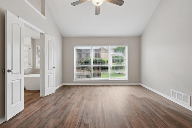 empty room featuring a ceiling fan, baseboards, wood finished floors, vaulted ceiling, and visible vents