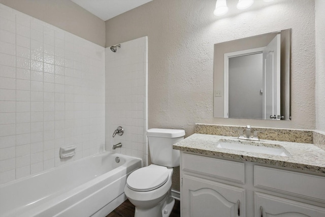 bathroom with vanity, a textured wall, shower / bathtub combination, and toilet