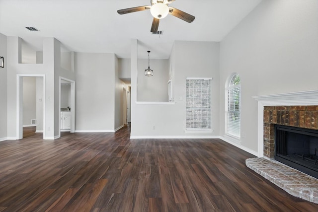 unfurnished living room featuring a ceiling fan, visible vents, dark wood-type flooring, and a towering ceiling