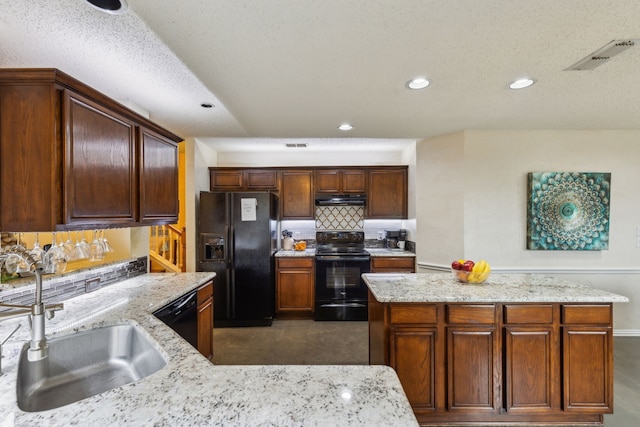 kitchen featuring visible vents, a sink, light stone counters, black appliances, and under cabinet range hood